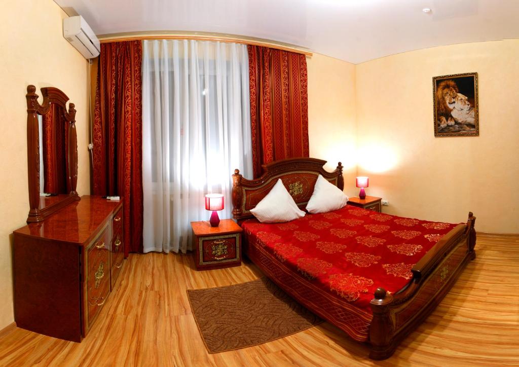 a bedroom with a large red bed with two lamps at De Luxe in Khmilnyk