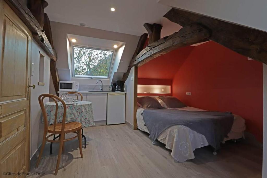 a bedroom with a bed and a table and a kitchen at Le Fiege gîte cosy et confort in Torchamp