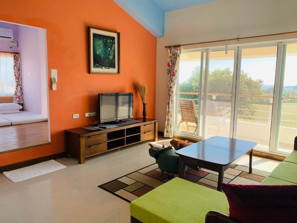 a living room with orange walls and a tv at Kenting COMIC B&amp;B in Hengchun South Gate