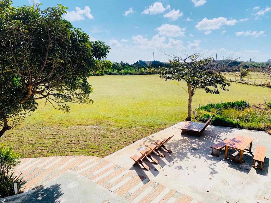 un gruppo di panchine seduti accanto a un grande campo di Kenting COMIC B&B a Città Vecchia di Hengchun