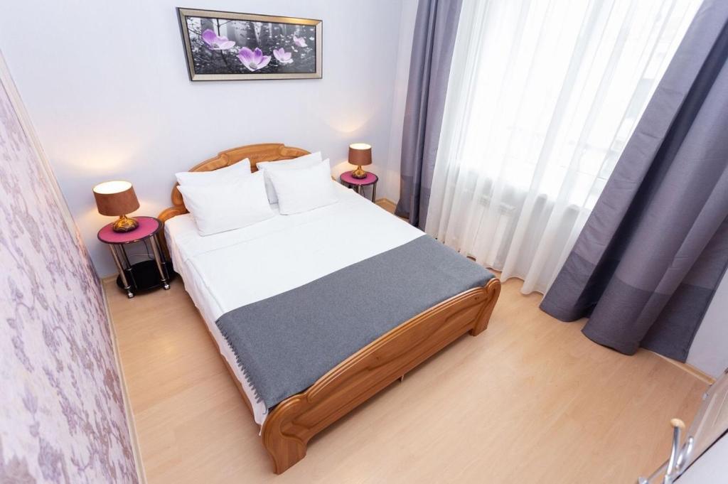 a small bedroom with a bed and two lamps at VIP Apartments 24/7 in Minsk