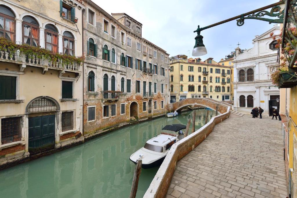 a boat in a canal with buildings and a bridge at Appartamento vista canale - Sant'Antonin in Venice