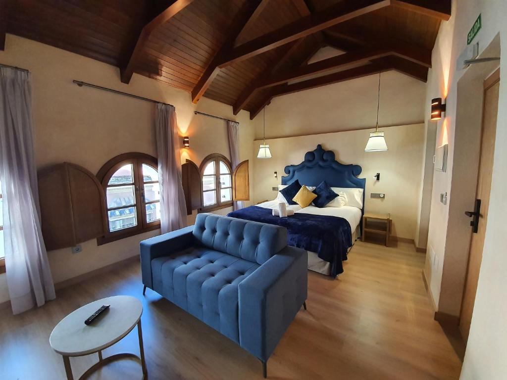 a bedroom with a blue bed and a couch at Boutique Puerta Real in Seville