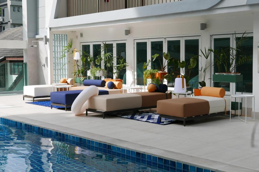 A sunny poolside terrace with modular sofas, loungers and potted plants.