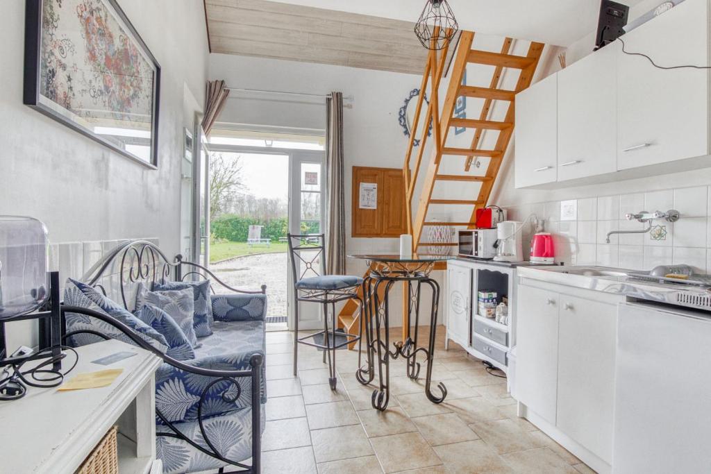 uma cozinha com armários brancos e uma mesa e cadeiras em Gite Barbey em Sainte-Marie-du-Mont
