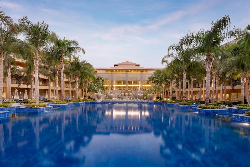 un complejo con piscina frente a un edificio con palmeras en Dusit Thani LakeView Cairo, en El Cairo