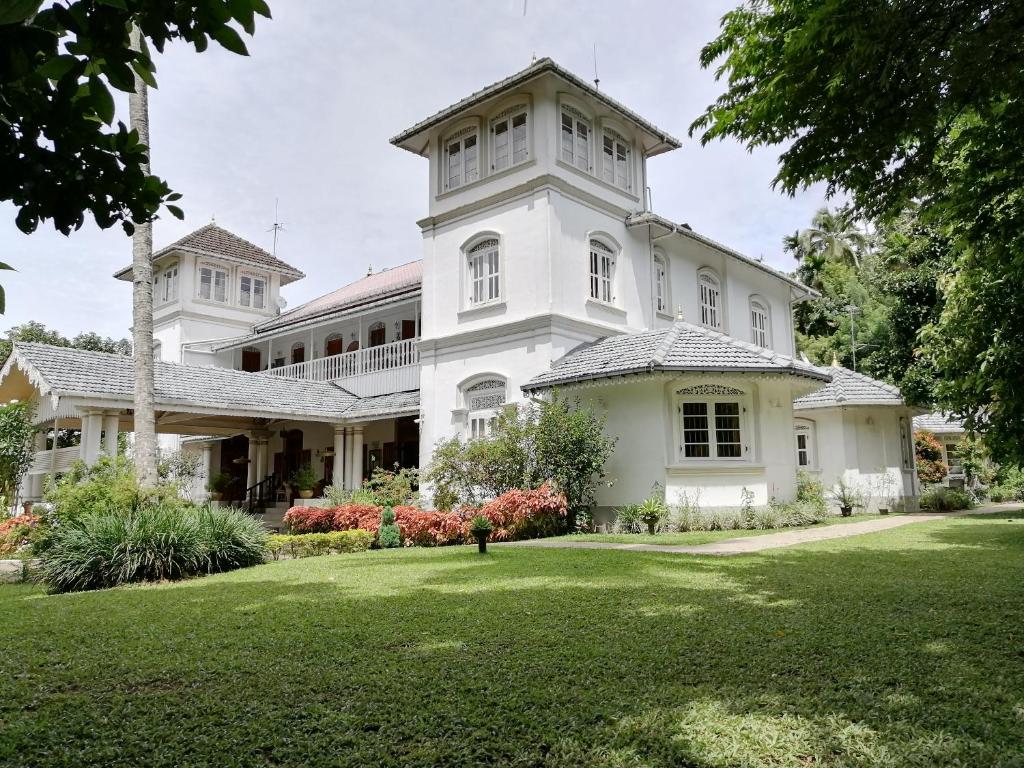 a large white house with a grass yard at Manor House-Kandy in Kandy