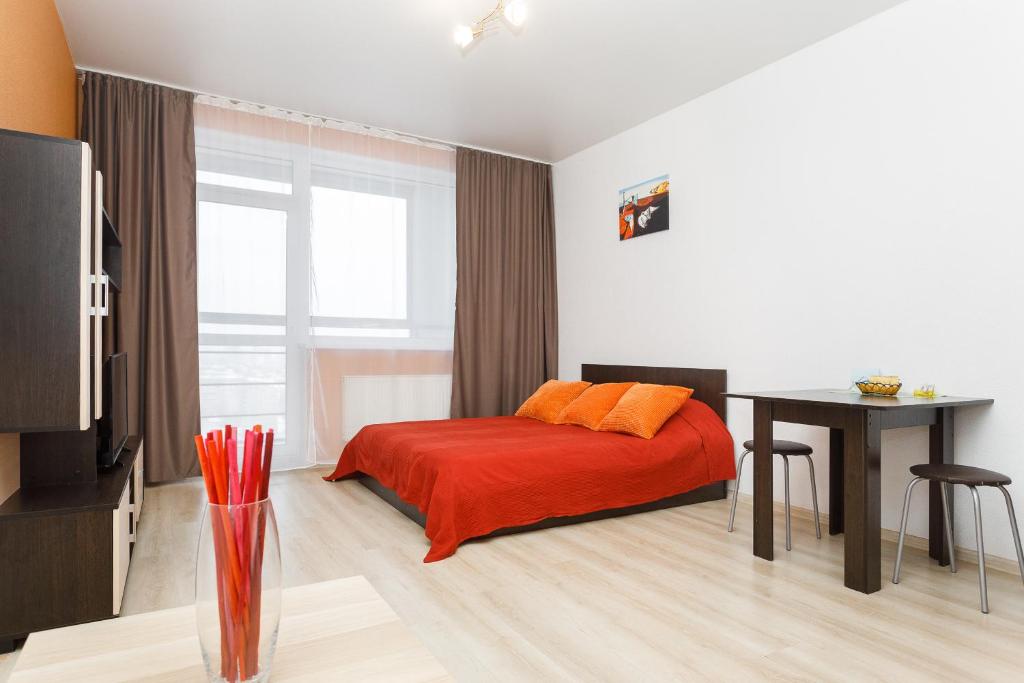 1 dormitorio con cama con almohadas de color naranja y mesa en EtazhiDaily at Studencheskaya, en Yekaterinburg