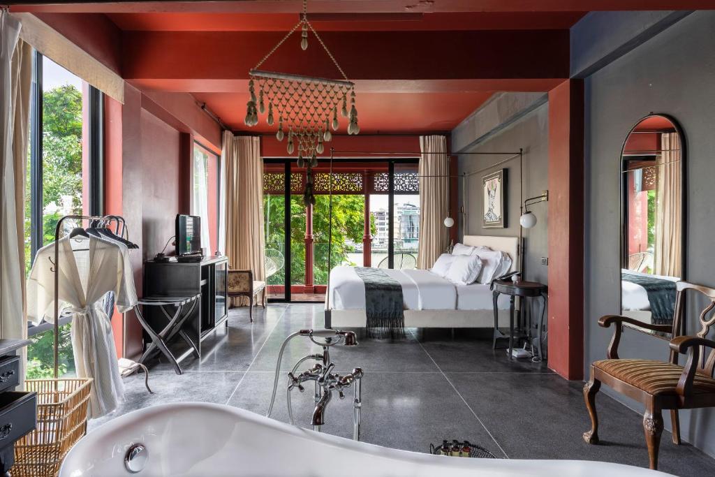 een slaapkamer met een bed en een bad bij Amdaeng Bangkok Riverside Hotel - SHA Plus Certified in Bangkok