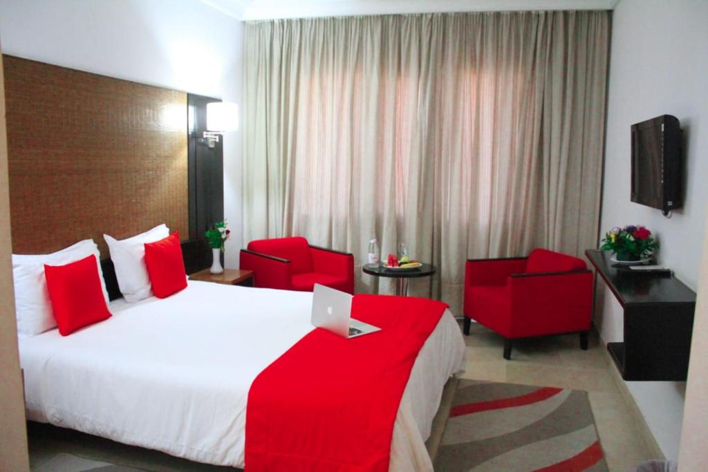 Habitación de hotel con 1 cama y 2 sillas rojas en hôtel LE PACHA en Túnez