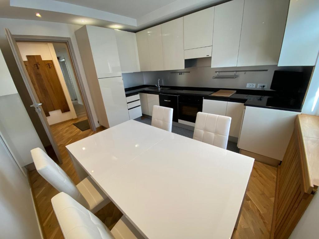 a kitchen with a white table and white chairs at Isabel in Pinzolo