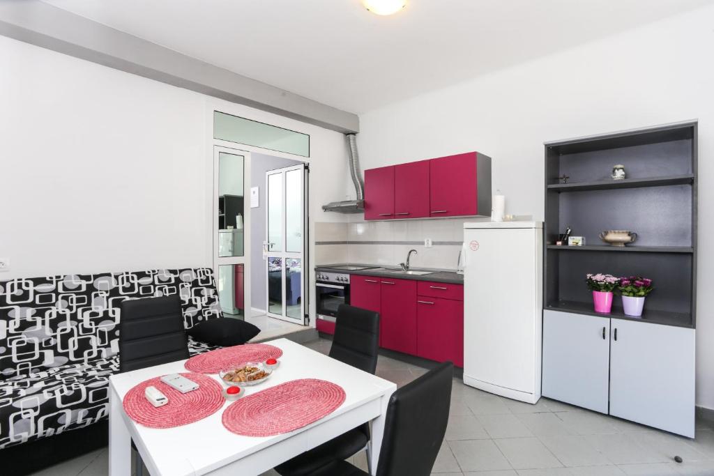 a kitchen with a white table and red cabinets at Apartment Saulan in Dubrovnik