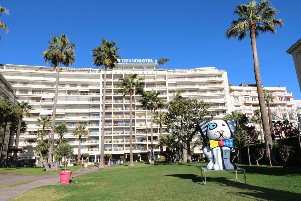 ein großes Gebäude mit einer Katzenstatue davor in der Unterkunft Beautiful studio at the Grand Hotel Residence with sunny balcony 138 in Cannes