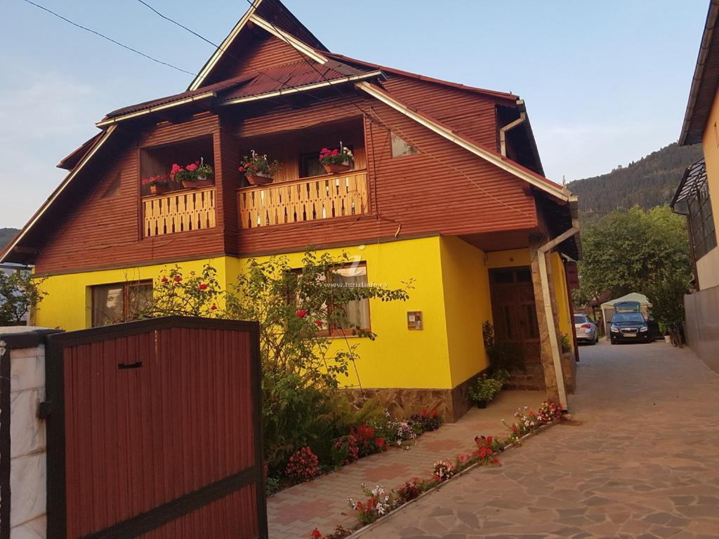 ein gelbes und braunes Haus mit einem Balkon in der Unterkunft Camere de închiriat Floarea reginei in Vişeu de Sus
