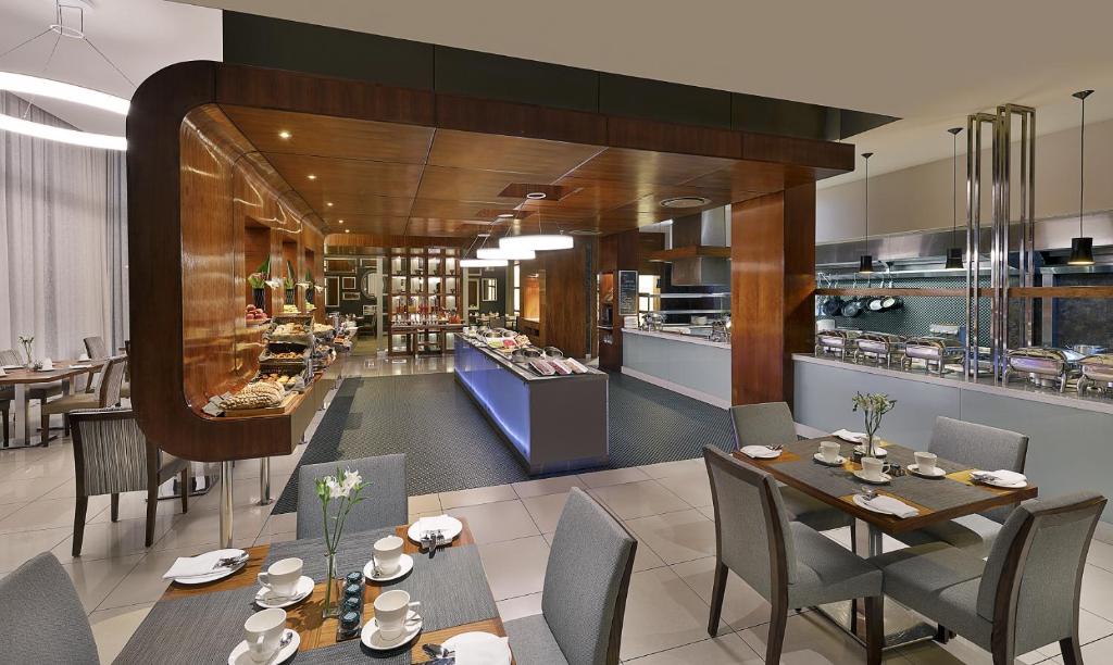 un restaurante con mesas y sillas y una cocina en The Residences at Crystal Towers, en Ciudad del Cabo