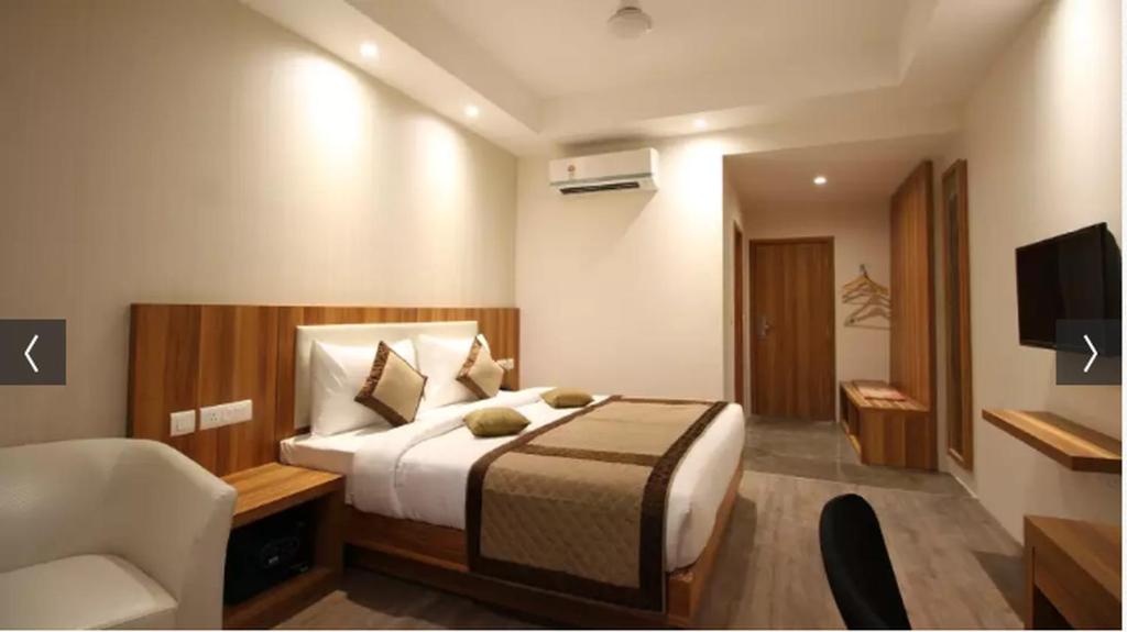 a bedroom with a bed and a chair and a television at Hotel Le Roi Raipur at Raipur Railway Station in Raipur
