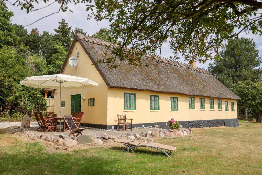 a yellow house with chairs and an umbrella at Sandet in Borre