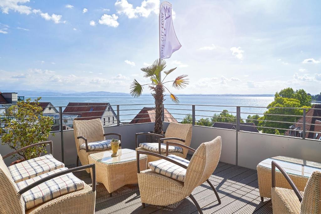 Un balcón con sillas y mesas y vistas al océano. en Hotel City Krone en Friedrichshafen