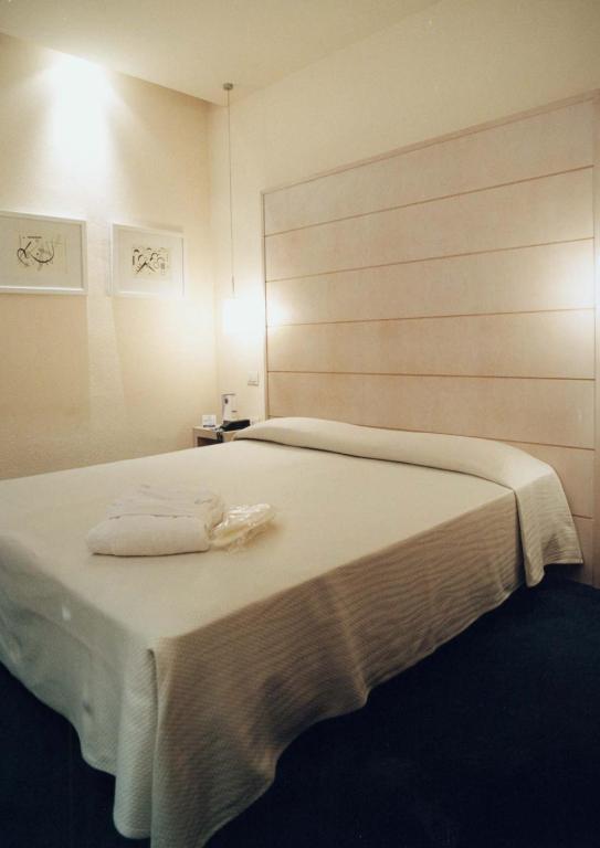 1 dormitorio con 1 cama blanca grande y 2 almohadas en Hotel First, en Calenzano