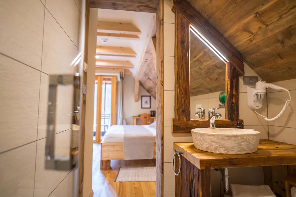 a bathroom with a sink and a mirror and a bed at Tourist Farm Šenkova Domačija in Zgornje Jezersko