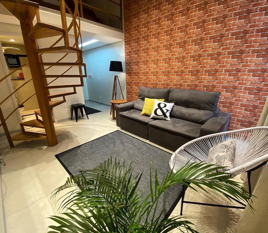 uma sala de estar com um sofá e uma parede de tijolos em LOFT46 EM De MARILIA em Marília