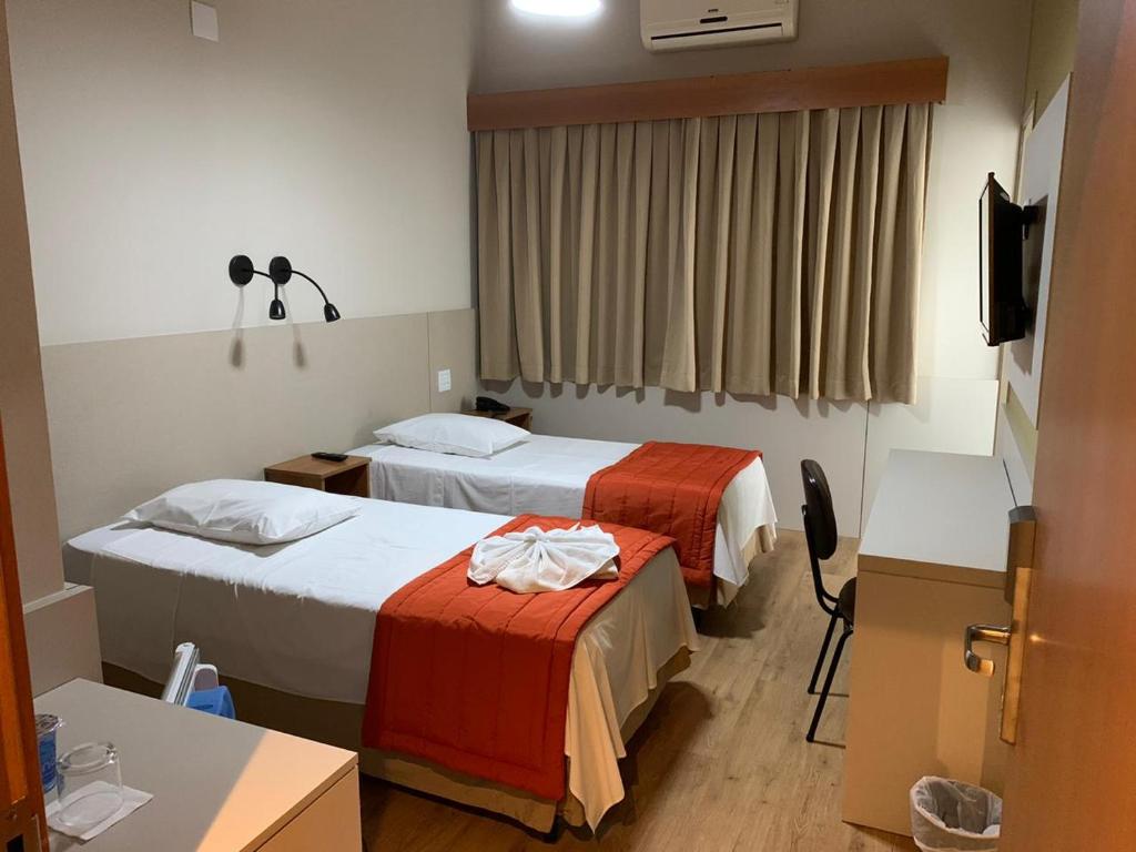 um quarto de hotel com duas camas e uma televisão em Hotel Cisne em São Paulo