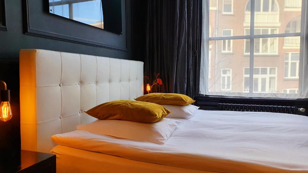 a bed with two pillows sitting next to a window at Residenz Stadslogement in The Hague