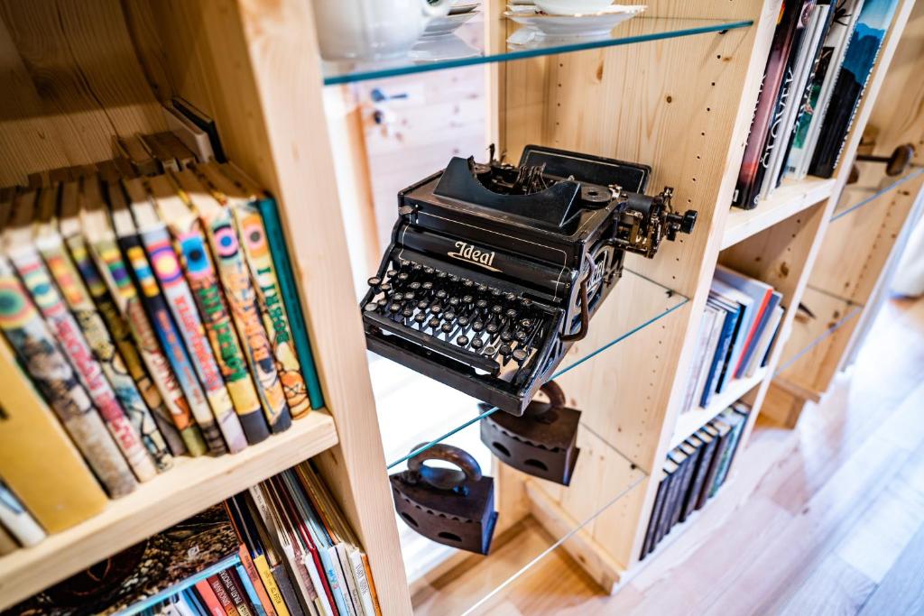 an old typewriter on a shelf of books at Tourist Farm Šenkova Domačija in Zgornje Jezersko