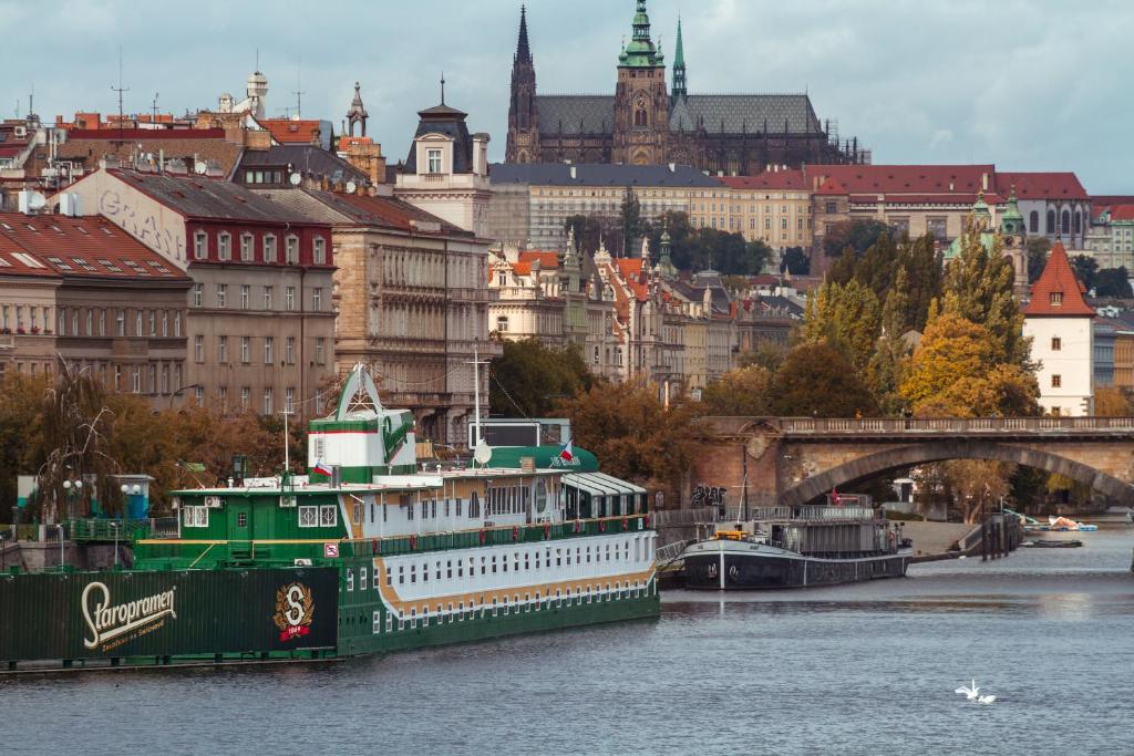 a large green boat on the river in a city at Admiral Botel in Prague