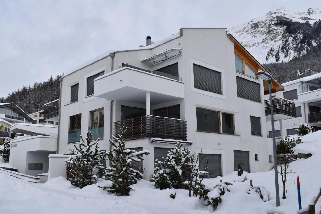 un bâtiment blanc avec de la neige devant une montagne dans l'établissement Curvér 3002 Ir Apart Irene, à Lenz
