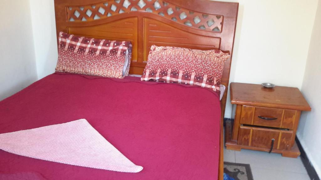 a bedroom with a bed with pink sheets and a table at Yabem Guest House in Addis Ababa