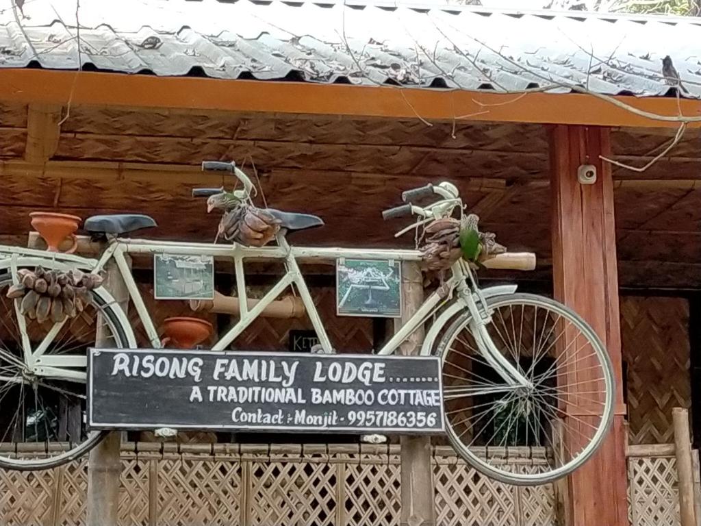 dos bicicletas están unidas a un cartel frente a un edificio en Risong Family Guest House, en Majuli
