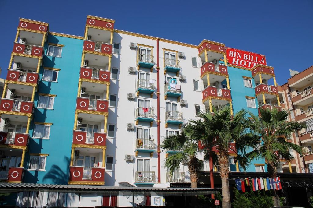 a building with colorful balconies and palm trees at BIN BILLA HOTEL in Alanya
