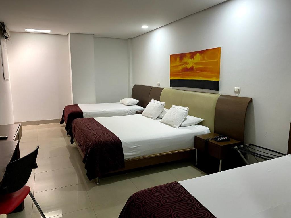 Habitación de hotel con 2 camas y escritorio en Hotel Merlott 70, en Medellín