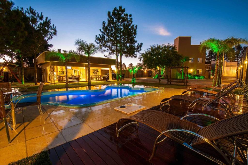 a swimming pool with chairs next to a building at Viageiro Casa Hotel in Pelotas