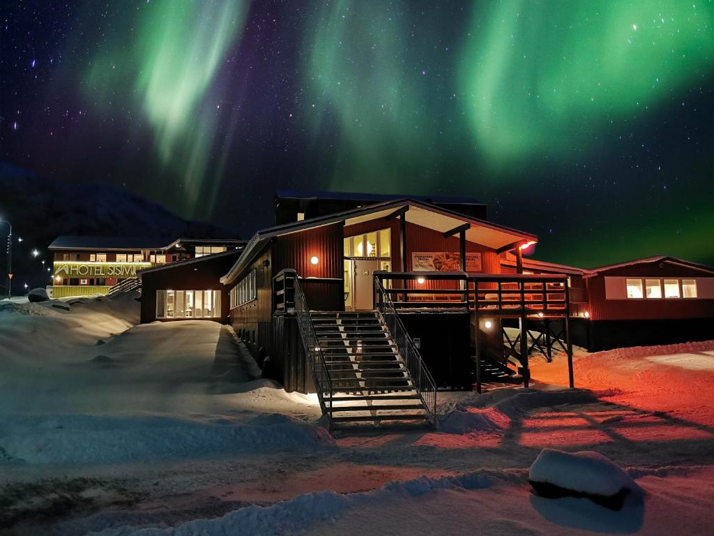 a cabin in the snow under the northern lights at Hotel Sisimiut in Sisimiut