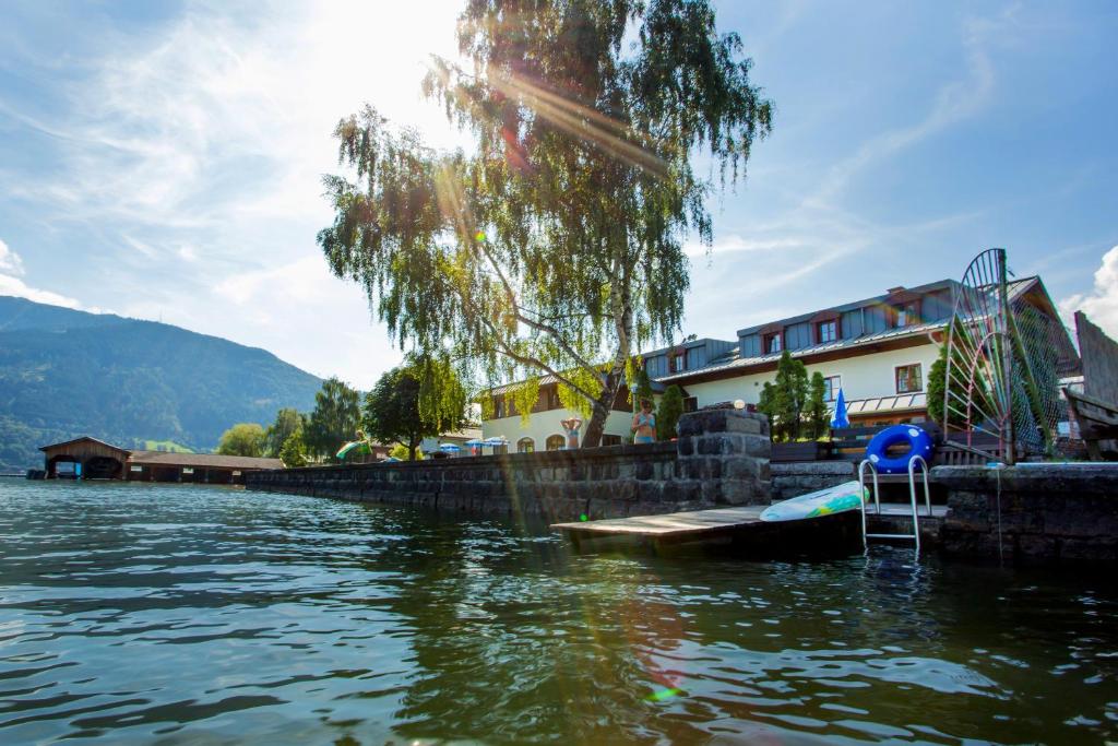 a view of a lake with a house and a boat at Junges Hotel Zell am See in Zell am See