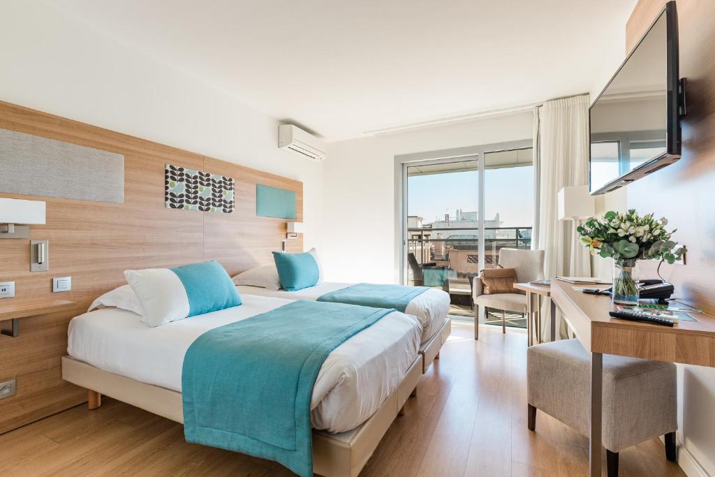 a hotel room with a bed and a desk and a desk at Hôtel Hélios in Juan-les-Pins