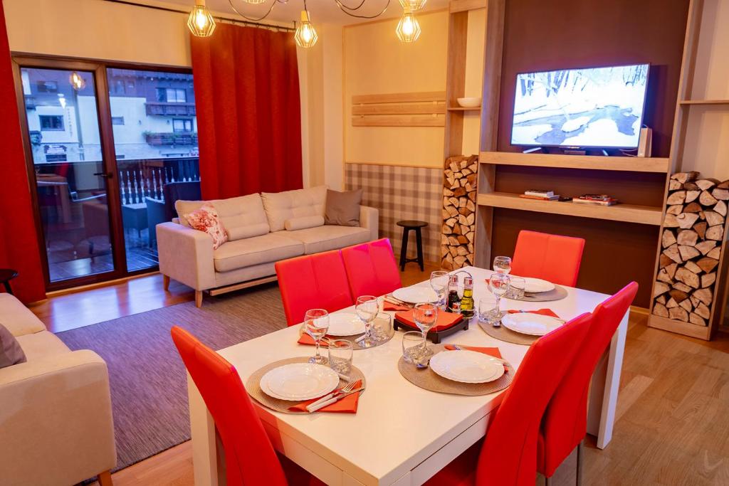a dining room with a table and red chairs at Clabucet Nest DeLuxe Apartment in Predeal