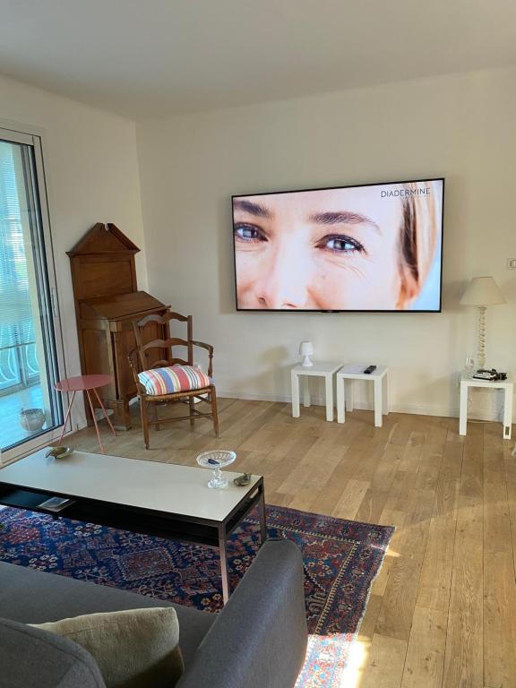 un salon avec une télévision à écran plat au mur dans l'établissement Le murât, à Six-Fours-les-Plages