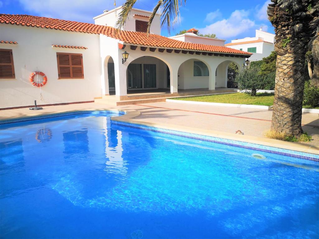 a large blue swimming pool in front of a house at Villa MARTINA in Cala en Forcat