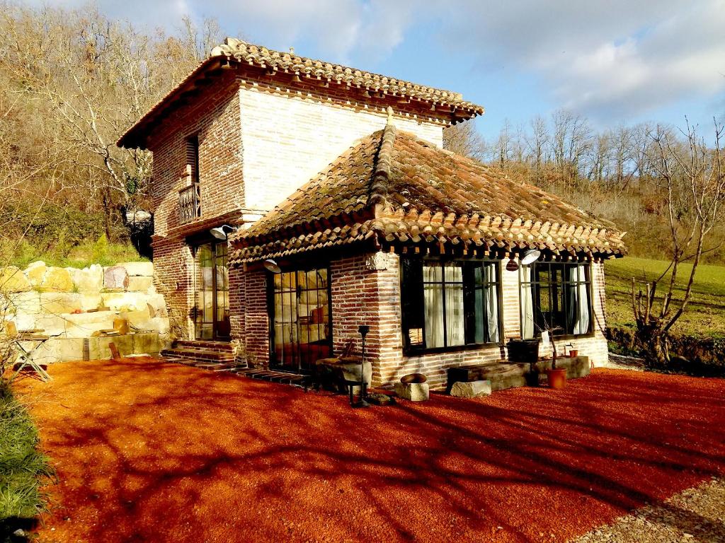ein kleines Backsteinhaus mit einem Dach auf einem Hof in der Unterkunft la fermette des grains dorés in Lafrançaise