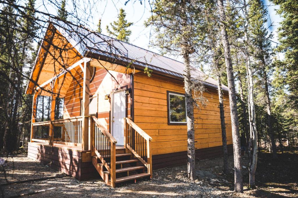 eine Hütte im Wald mit einer Veranda und einer Treppe in der Unterkunft Denali Wild Stay - Redfox Cabin, Free Wifi, private, sleep 6 in Healy