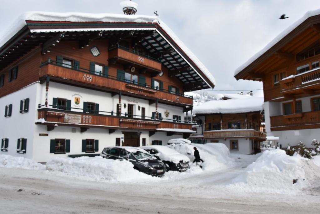 a snow covered building with cars parked in the snow at Stöcklbauer in Kirchberg in Tirol