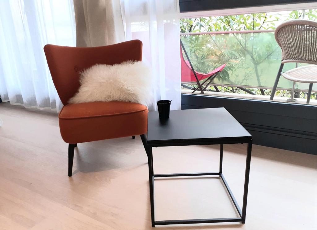 una sedia rossa seduta accanto a un tavolo e a una finestra di St Germain en Laye- La défense 17mn -STUDIO FIBRE -Terrasse a Le Pecq