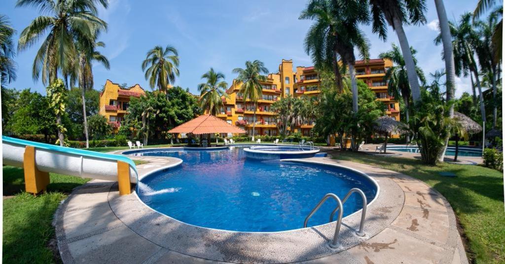 una piscina del resort con un resort sullo sfondo di Hotel Puerta Del Mar Ixtapa a Ixtapa
