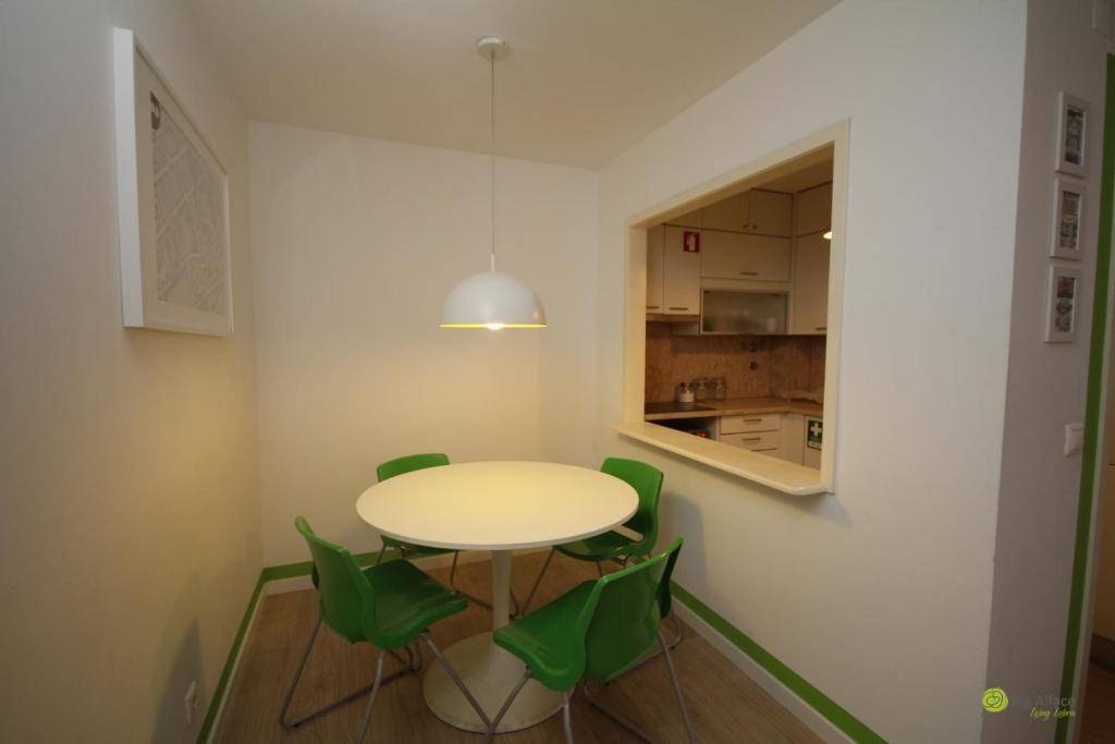 a dining room with a table and green chairs at Big Alface in Lisbon