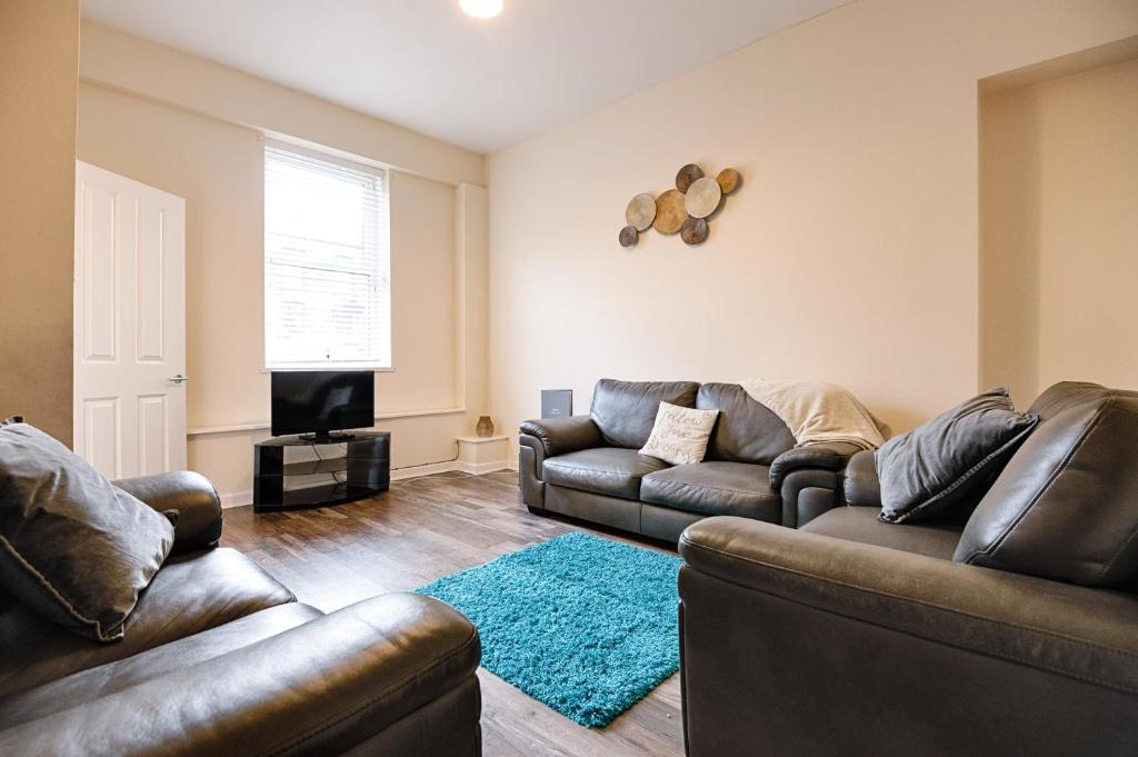 a living room with two leather couches and a television at Perfect Location with Parking - Jersey House - TV in every Bedroom! in Swansea