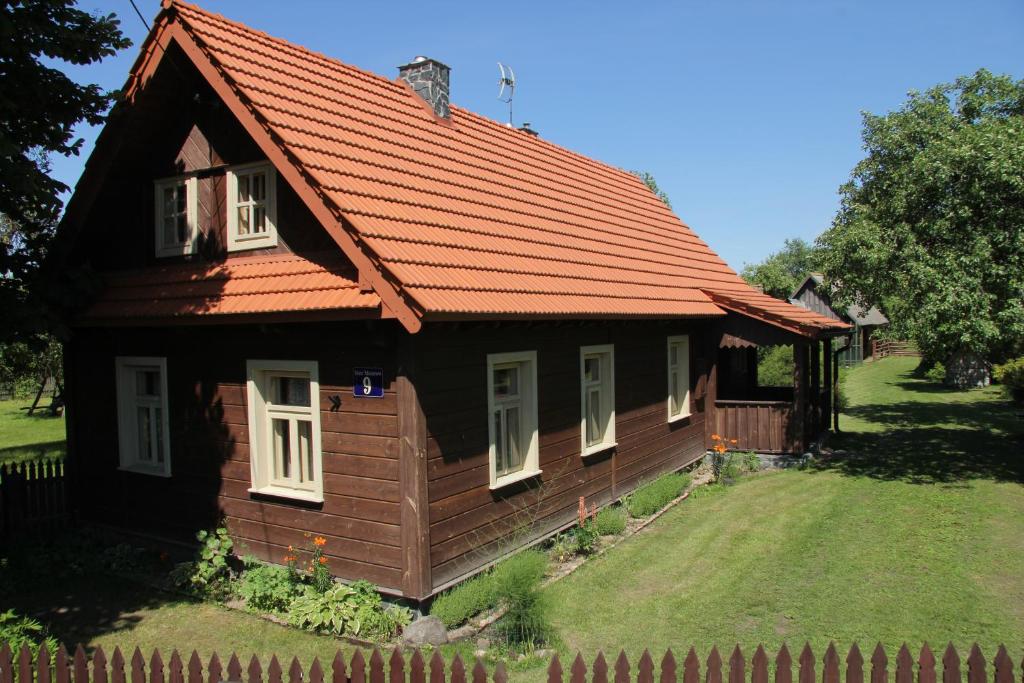 a small wooden house with an orange roof at Folwark Stare Masiewo TRYBA in Narewka