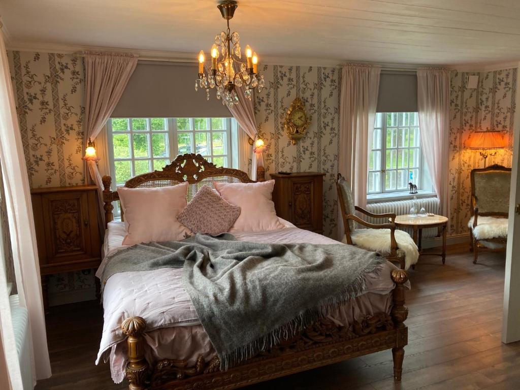 1 dormitorio con cama y lámpara de araña en Wedevågs Herrgård en Vedevåg